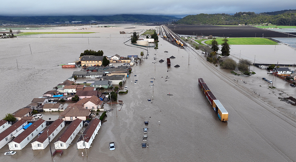 Aerial view of a residential area and train tracks submerged in floodwaters.