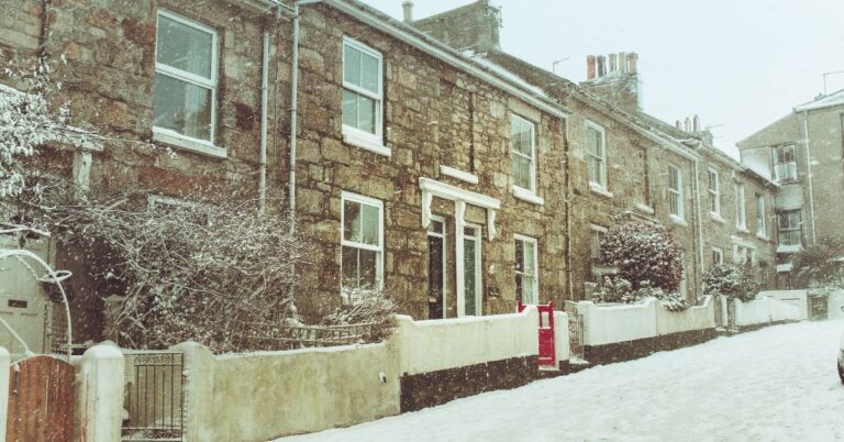 Snow-covered stone row houses on a street.