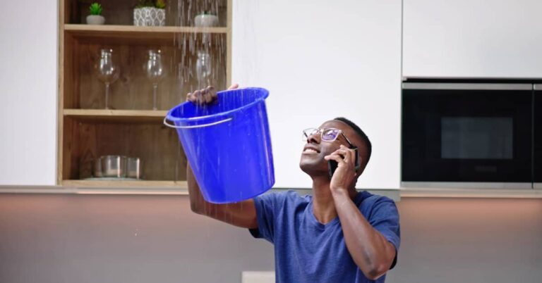 Man catching water in a bucket after damage to the roof | ATI Restoration