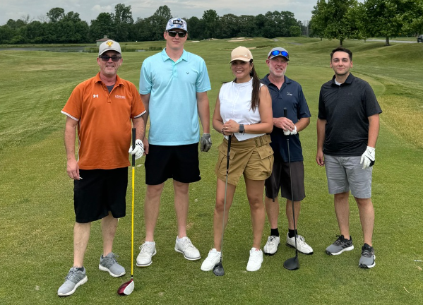Five golfers posing on a golf course.