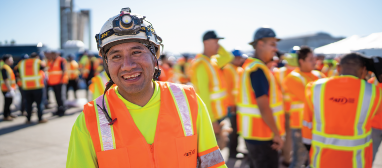 Smiling construction worker in hard hat and safety vest.